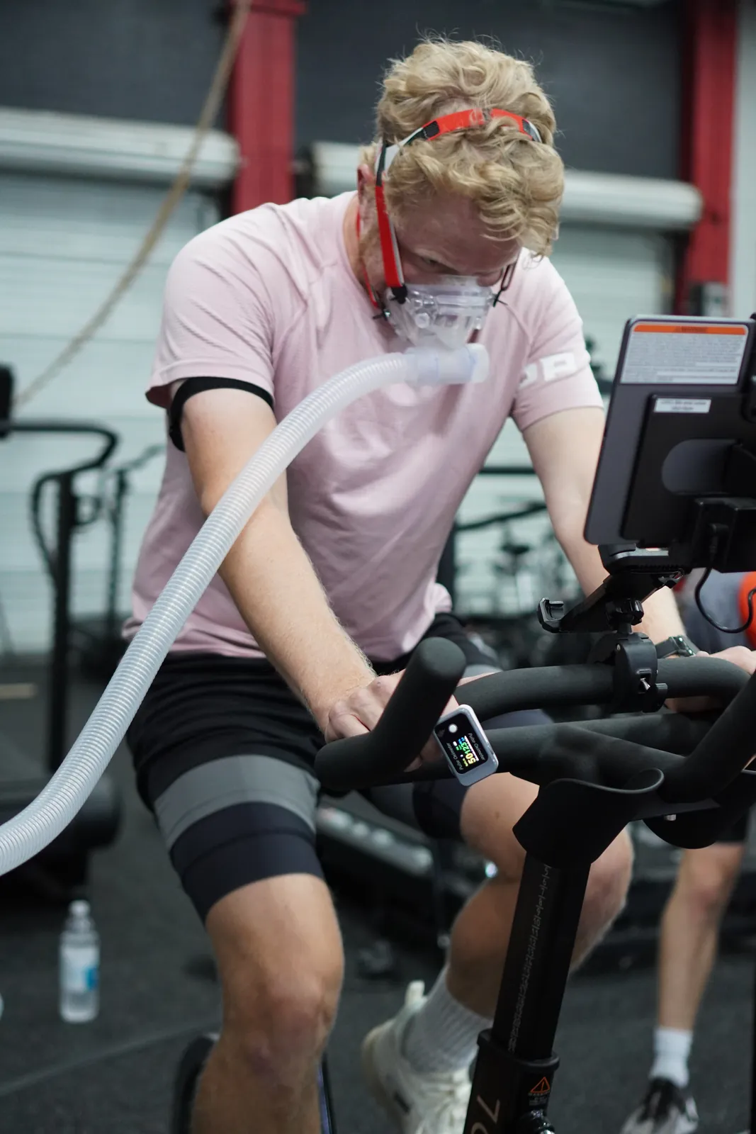 A member riding the bike in a PNOĒ mask during an active physiology test