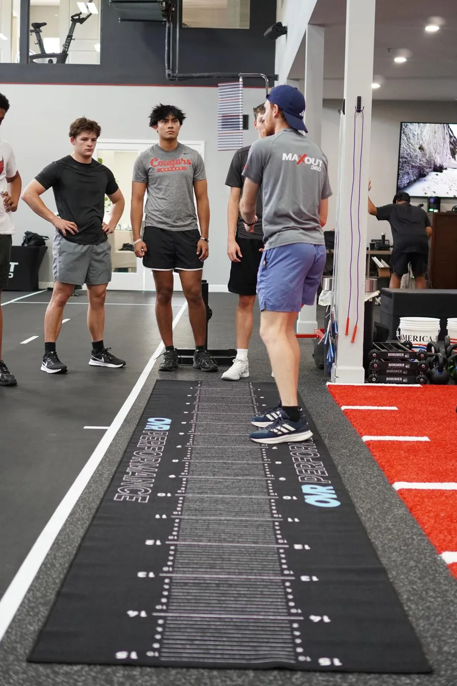 A coach talking athletes through a jump test on the measured mat